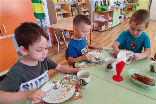 Дети с удовольствием кушают плов с курицей.